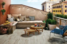 terrazzo-arredato-con-luci-divano-uscini-due-tavolinetti-rotondi-una-sedia