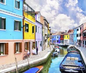via-di-venezia-con-case-colorate-gondola-e-fiume
