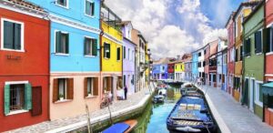 via-di-venezia-con-case-colorate-gondola-e-fiume