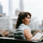donna-sorridente-che-sta-leggendo-un-libro-all-aria-aperta