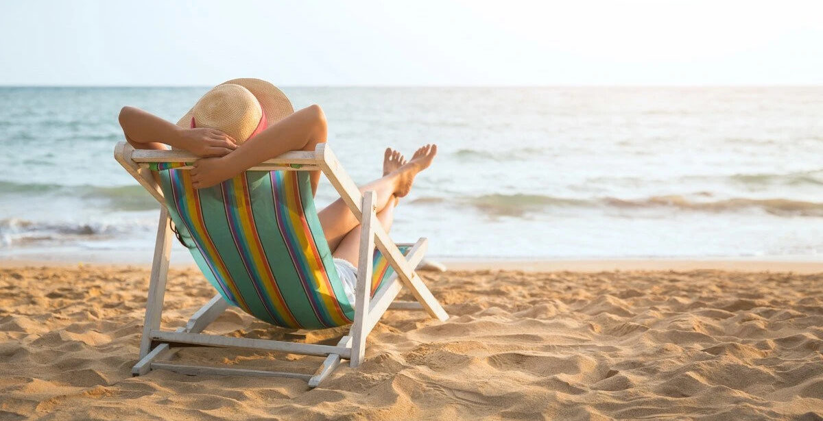donna-di-spalle-sulla-sdraia-prende-sole-mare-sabbia