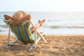 donna-di-spalle-sulla-sdraia-prende-sole-mare-sabbia