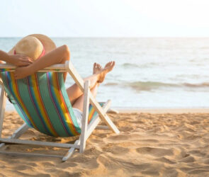 donna-di-spalle-sulla-sdraia-prende-sole-mare-sabbia