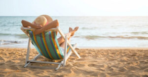 donna-di-spalle-sulla-sdraia-prende-sole-mare-sabbia